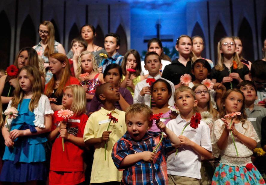 Preschooler Keltin Marazzi, front center, stands on stage with other school children during the memorial service.  