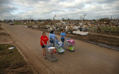 Left to right, Jaqi Castro, Angelica Morris-Smith and Cetoria Petties walk through a tornado ravaged neighborhood handing out supplies to residents and fellow volunteers on May 27.