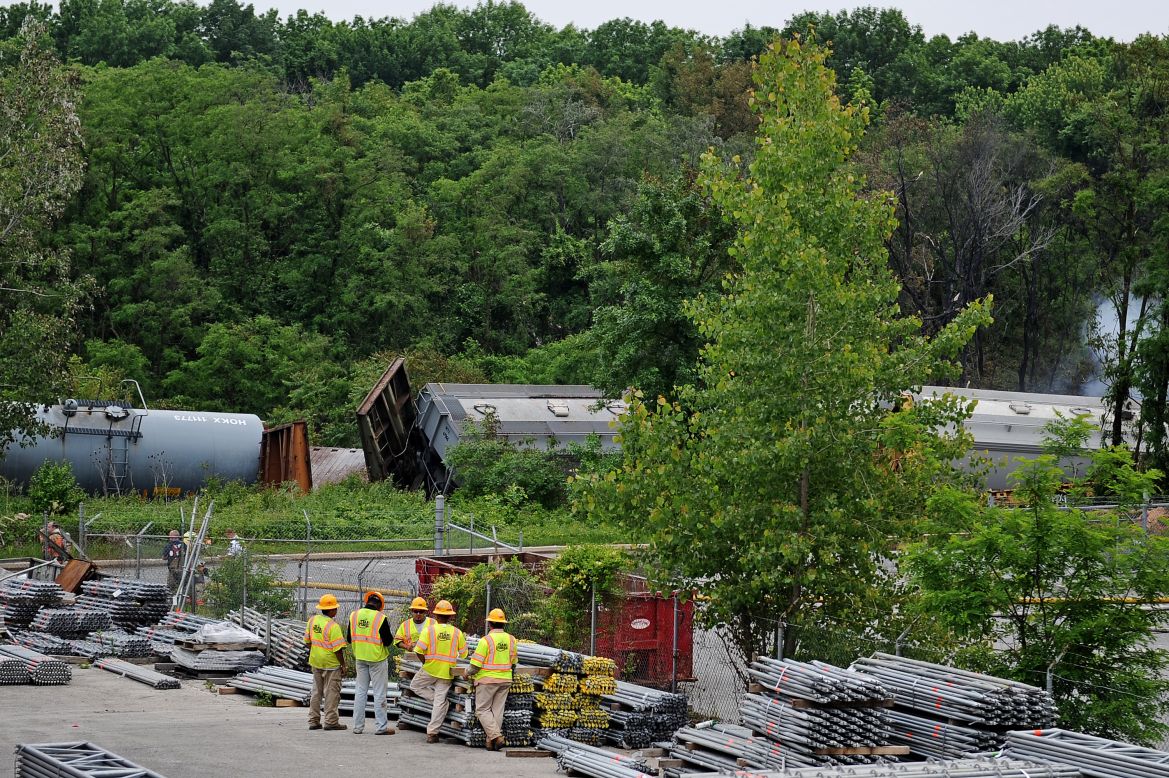 Workers gather around as damaged train cars from the derailment lie strewn along the tracks.