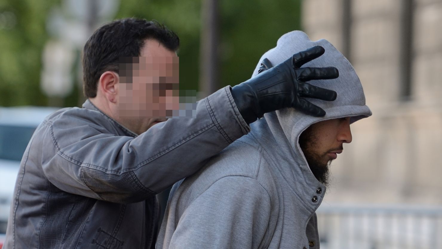 The suspected perpetrator (R) of the Sunday attack on a soldier is escorted to police headquarters in Paris on Wednesday.