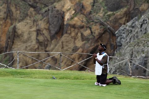 Hugo Benson, caddy of Finnish golfer Roope Kakko, kneels down on the 14th green and prays during the final round of the 2011 Madeira Islands Open.