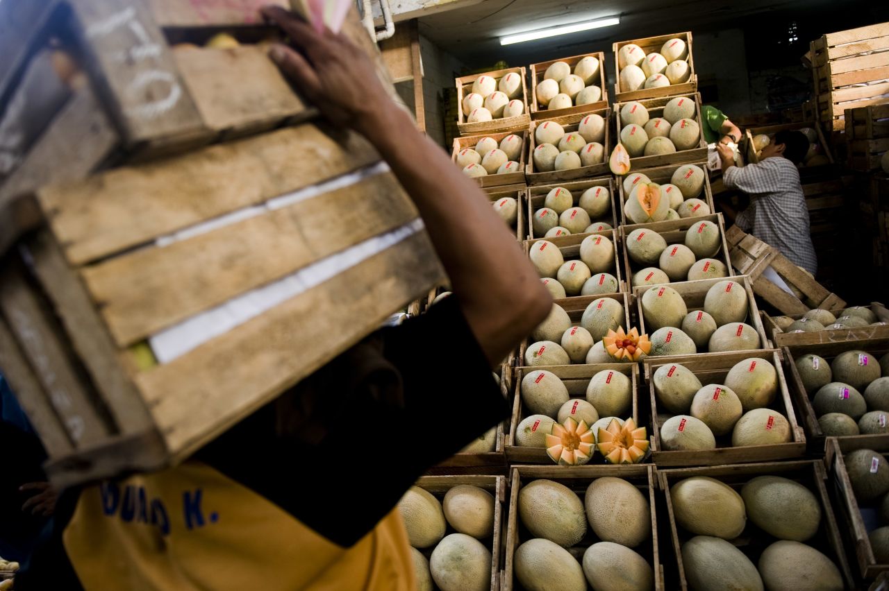A worker carries boxes at the wholesale fruit market in Lima.