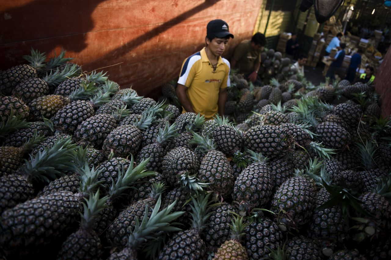 A vendor sells pineapples at the wholesale fruit market in Lima.
