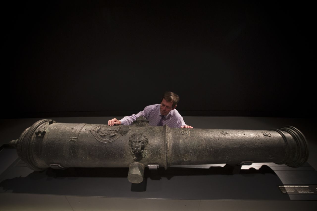 Maintenance Coordinator Brian Robinson poses next to a cannon recovered from the wreck.