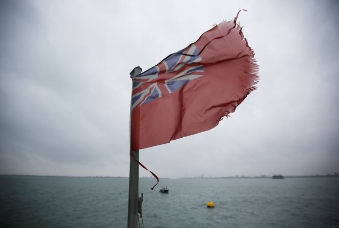 A red ensign flag flies on a ship at the location of the sinking of the Mary Rose which is marked by a yellow buoy.