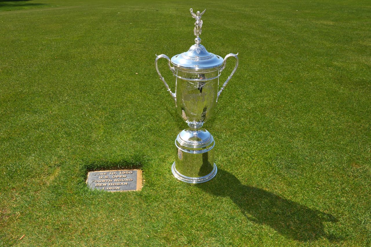 The U.S. Open trophy is paraded next to the plaque on the 18th hole which marks the point from which Hogan played his famous shot. 