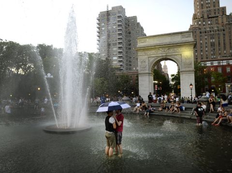 People cool off in a fountain at Washington Square Park in New York at dusk on Friday, May 31, as temperatures reached the 90s. 