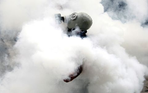 An activist wearing a gas mask is enveloped in a cloud of tear gas on May 31.