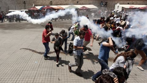 A crowd scatters during clashes on May 31, as one demonstrator throws back the tear gas canister that was launched by riot police.