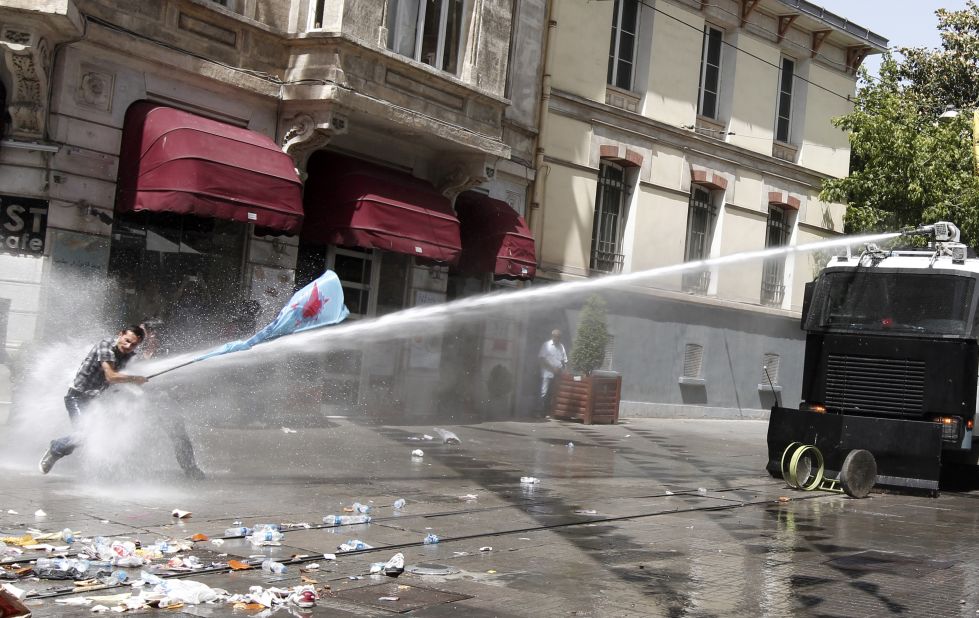 Protestors brace themselves as they are fired upon with a water canon by Turkish police forces.