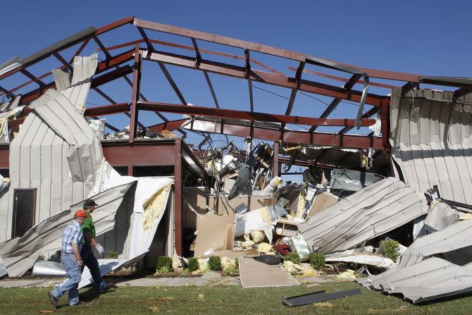Two men walk by a damaged OKC-West Livestock Market building near El Reno on June 1.