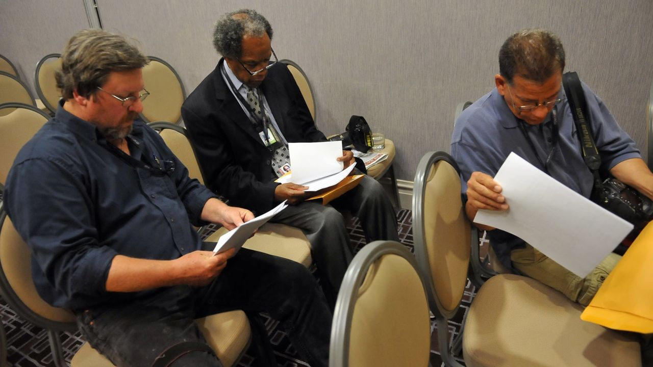 Photographers Tom Cruze, from left, John H. White and Brian Jackson look over paperwork during the mass layoff at the Chicago Sun-Times on May 30.