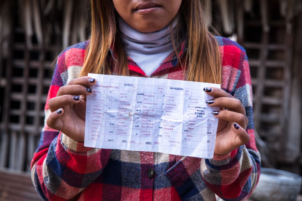 "We work under poor conditions, but we don't want to leave because other factories are too far." A factory worker shows her payslip. 