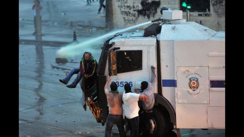 Protesters cling to a police vehicle mounted with a water canon in Istanbul on June 2.