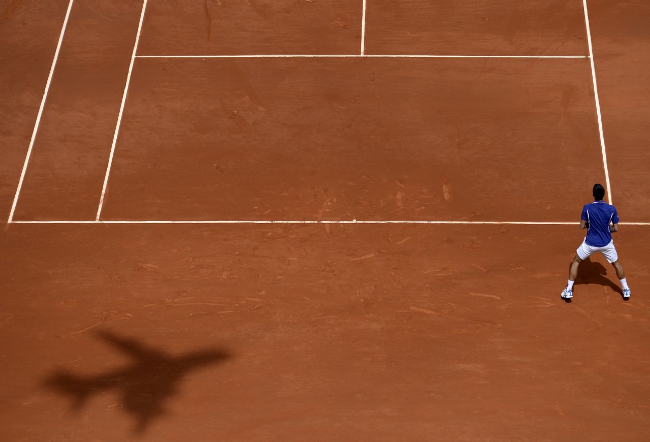 The shadow of a plane-shaped camera appears on the court as Djokovic waits for a serve from Kohlschreiber on June 3.
