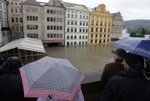 Onlookers watch the water rise around houses on the Vltava River in Prague. The Vltava was cresting Tuesday in the Czech capital, but areas downstream still faced rising waters.<br />