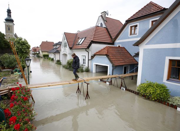 A women crosses a makeshift bridge over flooded streets in Unterloiben, Austria, on Tuesday, June 4.