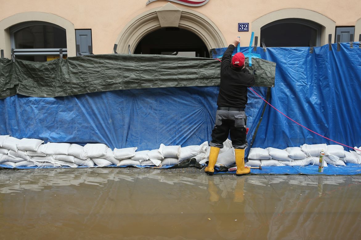 A resident adds a tarp to a restaurant on June 4, to help prevent damage from rising floodwaters from the nearby Elbe River in Pirna, Germany. 