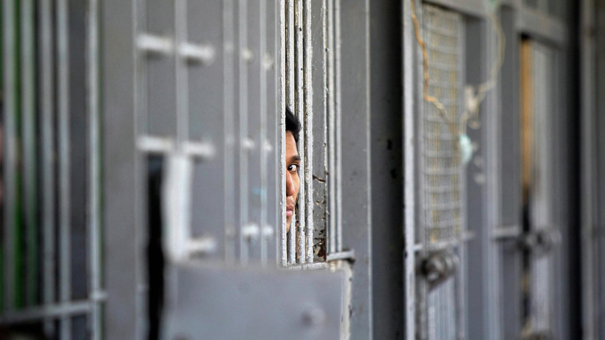 An inmate peers through the bars of a cell at the Federal District Penitentiary in Mexico City.
