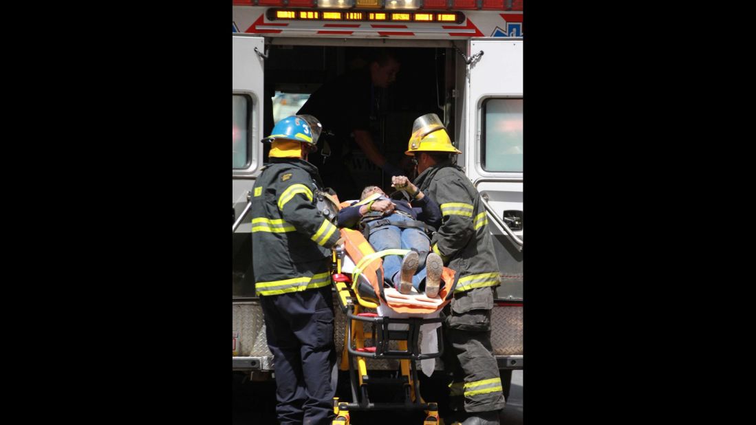 Emergency personnel load an injured person into an ambulance.