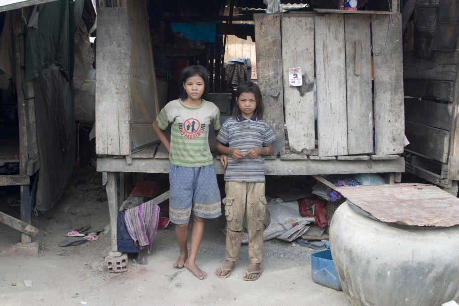 Sreyna, right, and her sister Salim stand in front of their house near the dump. They had no electricity or running water. 