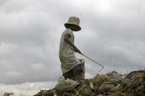 A girl searches for glass, plastic and metal at the landfill near Cambodia's capital. She and others have to combat flies, rats, snakes and the terrible stench. 