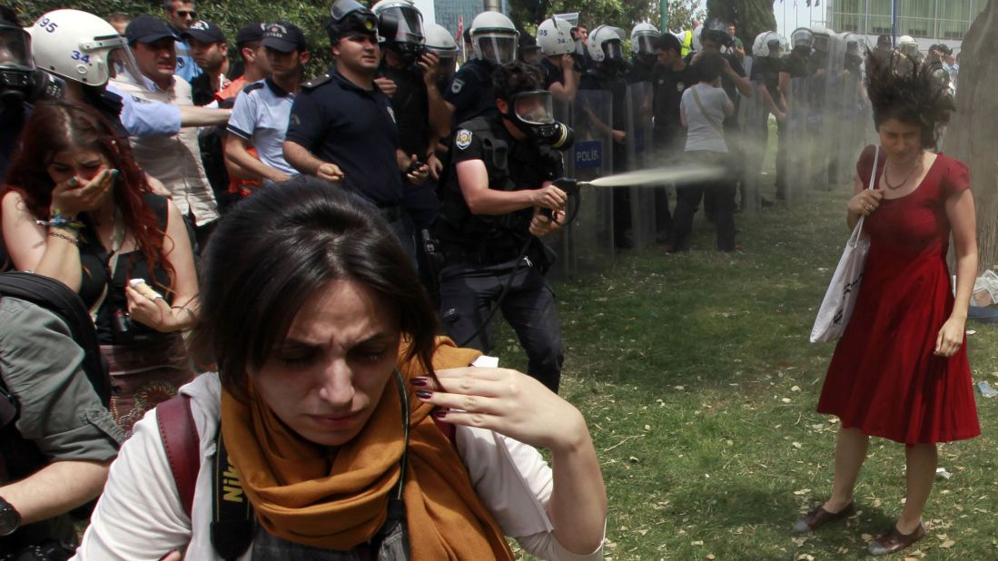 A riot police officer uses tear gas as people protest the destruction of a park for a pedestrian project in Istanbul's Taksim Square on May 28, 2013. The woman in red became the face of the protests.