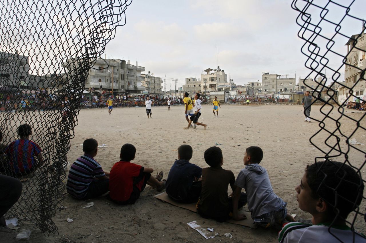Palestinian youths watch a local football match, just before sunset, at a refugee camp in Rafah, in the southern Gaza Strip, during the Muslim holy month of Ramadan on July 28, 2012. Sarsak grew up in Rafah, with football as his only distraction. "It runs through the family blood," he says.