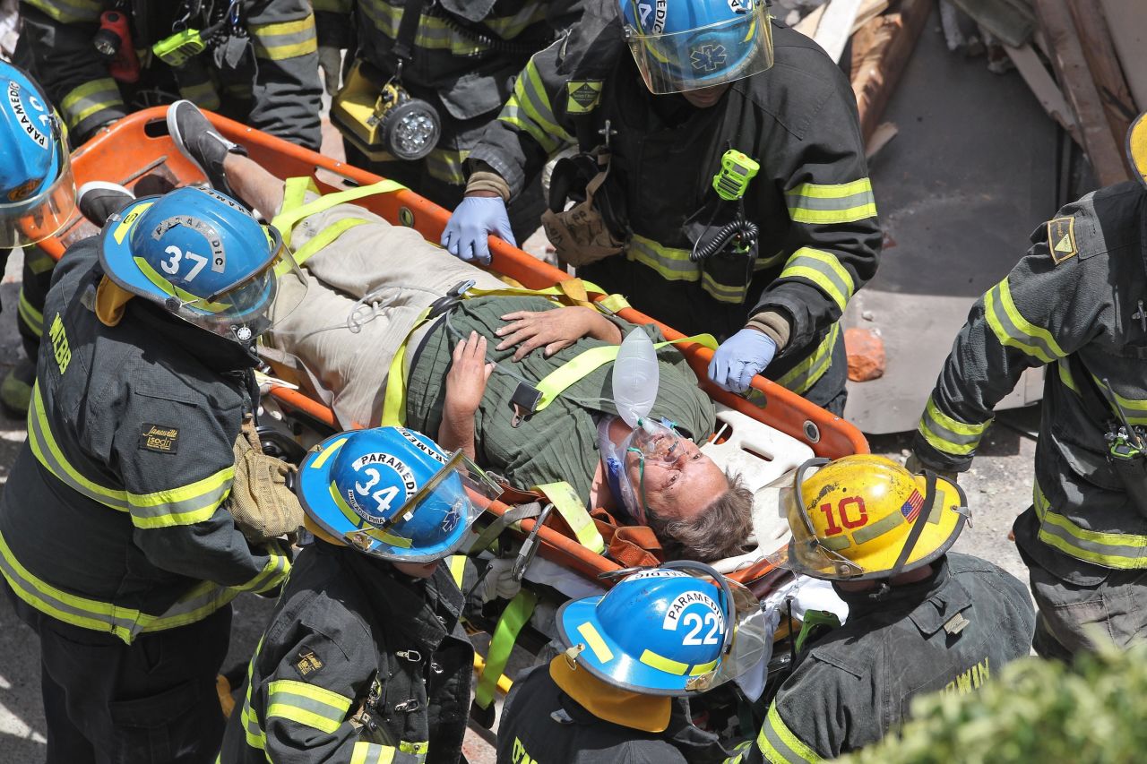 Firefighters carry a survivor from the rubble.