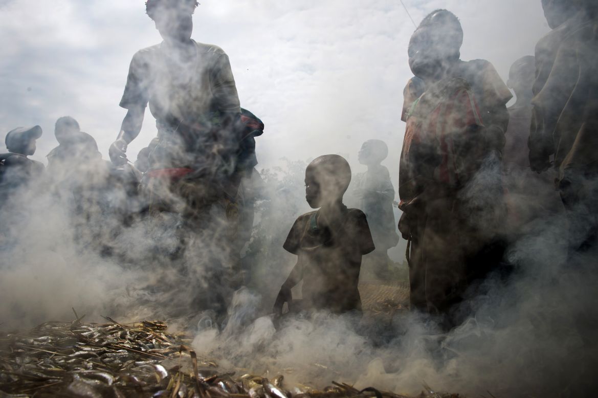 A group of Congolese gather around fish being smoked in the Mugunga camp near Goma.