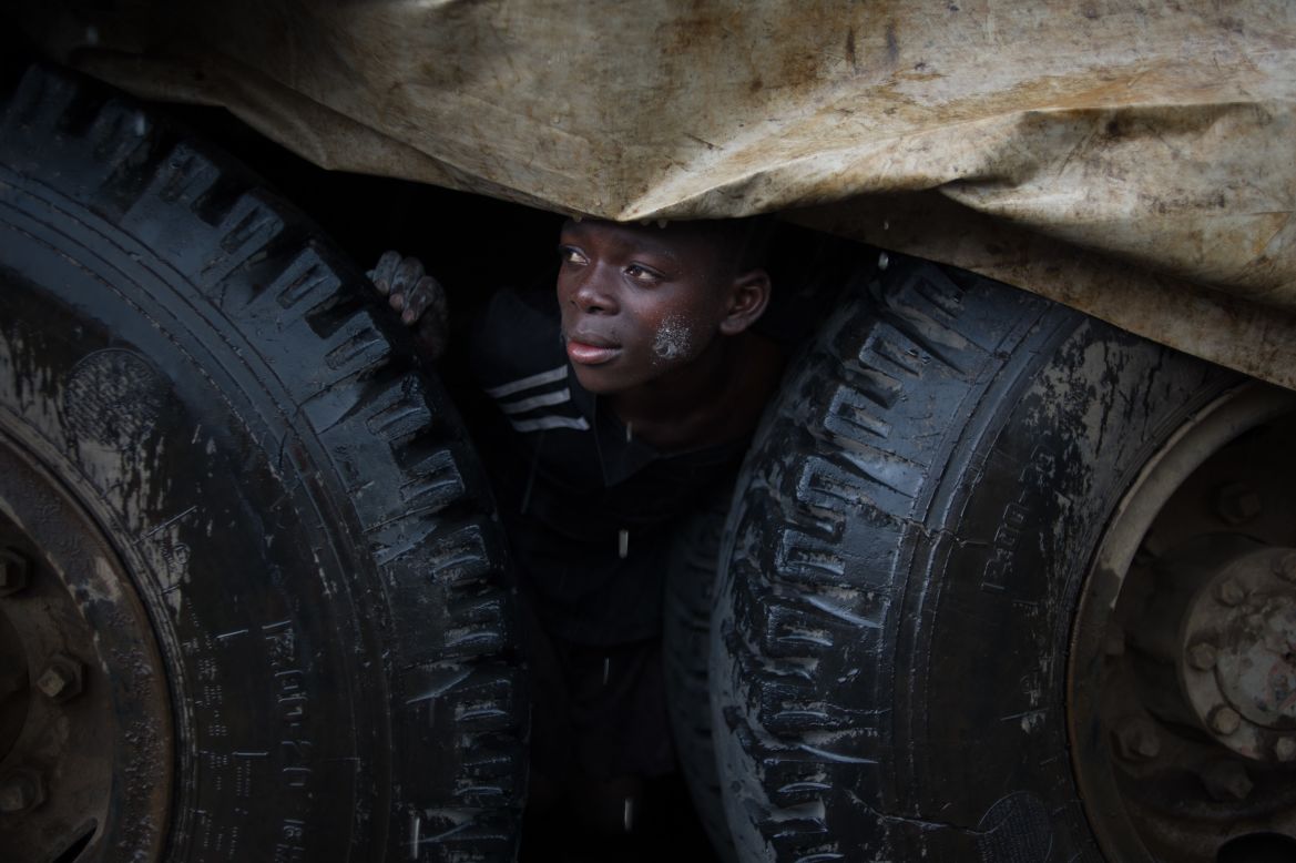 An internally displaced Congolese boy shelters from the rain under a truck in the Mugunga III camp.