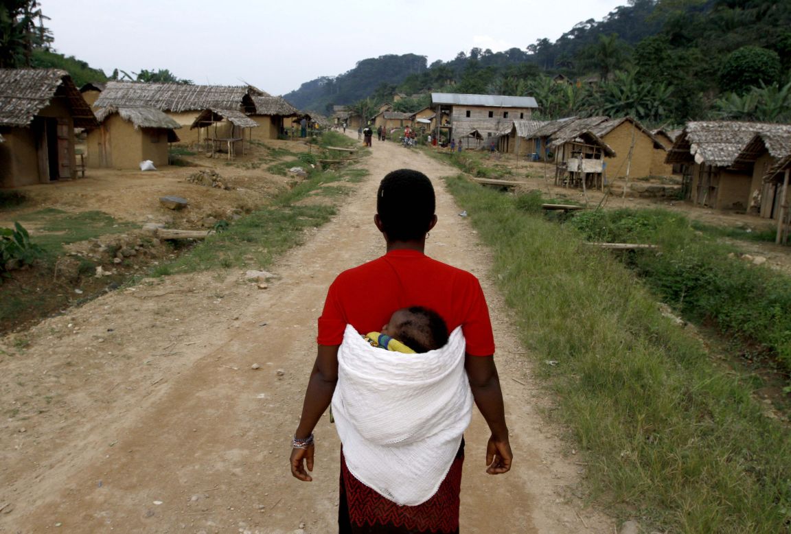 A woman walks with her child down the main road in the village of Luvungi.