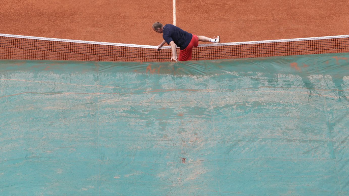 A court attendant covers the center court as rain falls over the Roland Garros stadium on June 6. The rain interrupted the semifinal match between Maria Sharapova and Victoria Azarenka.