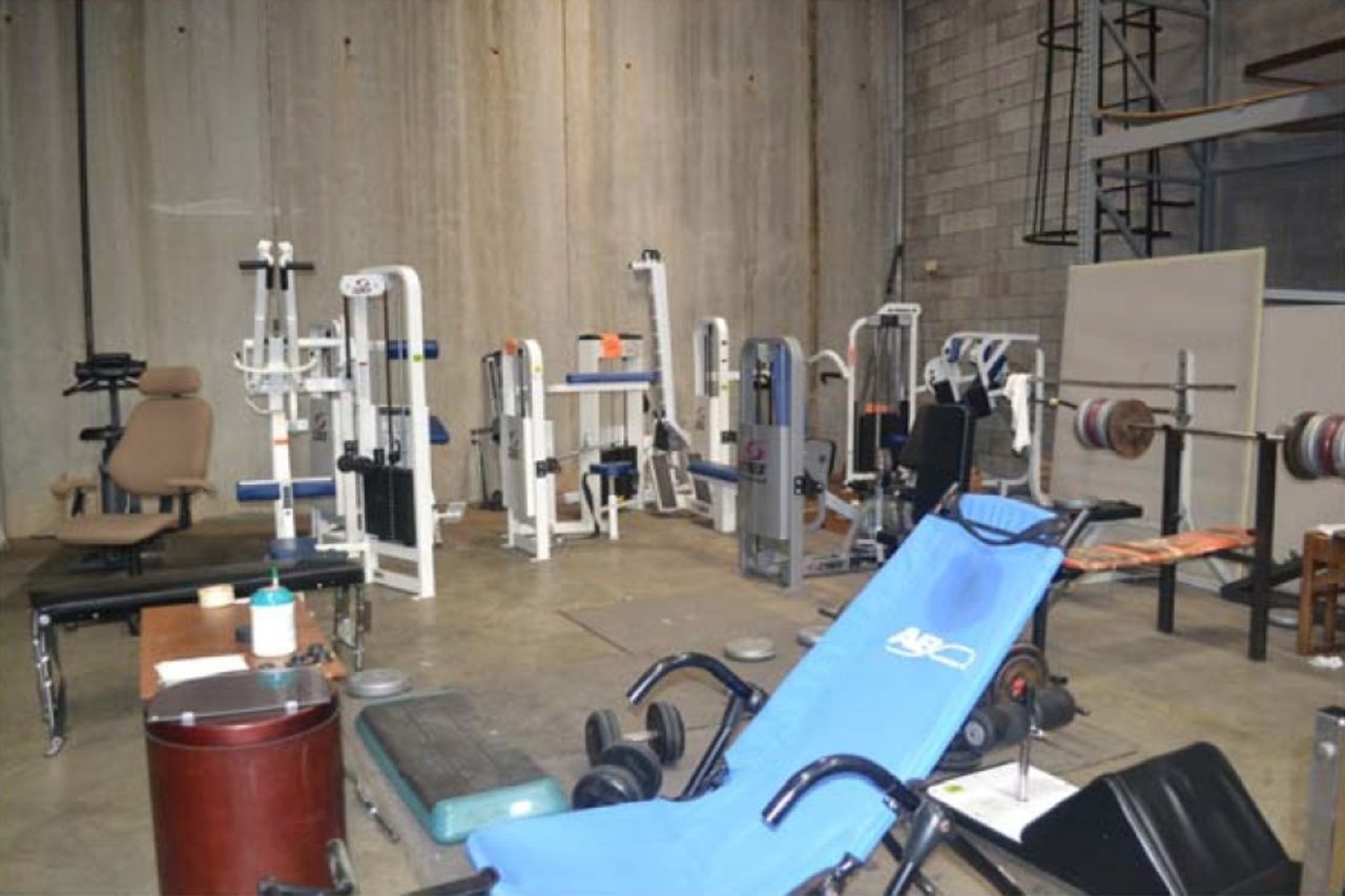 The gym was carpeted with floor tiles from storage and contained steno pads for recording workouts.