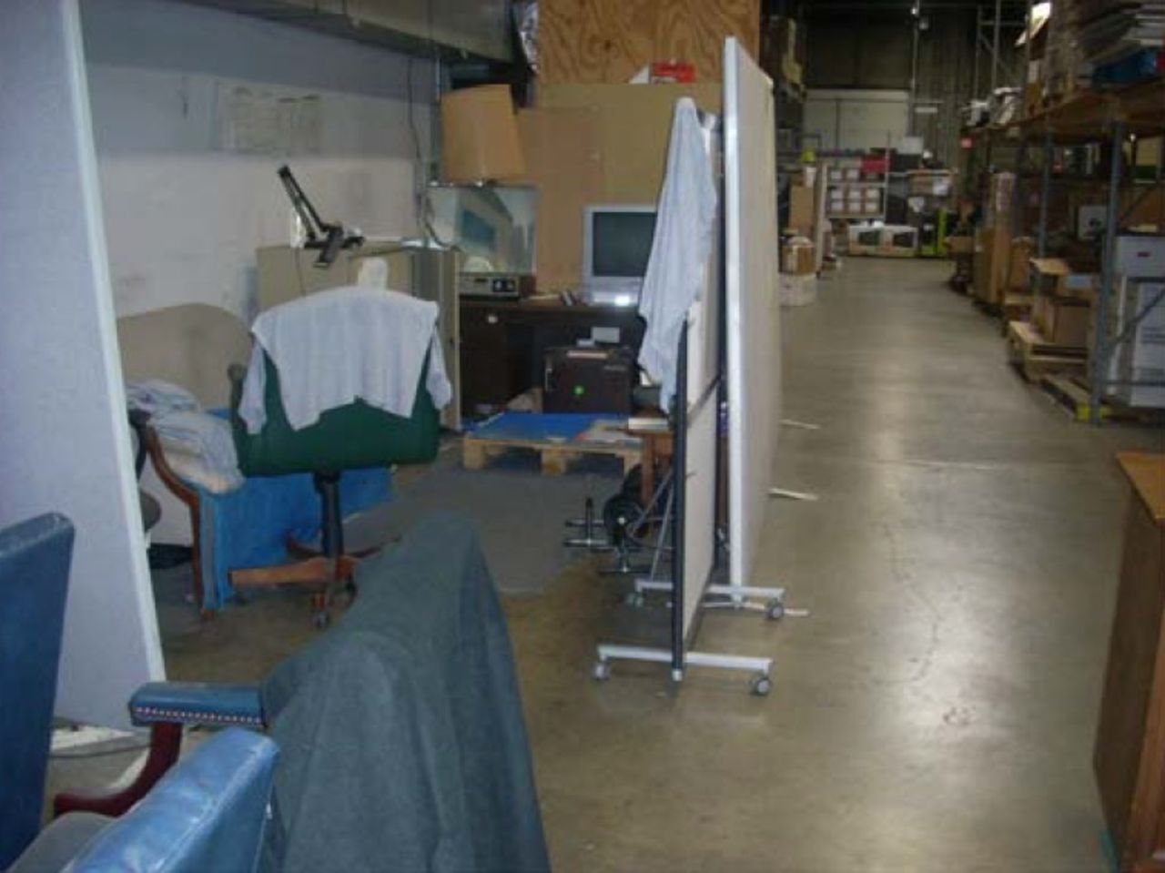 This lounge hidden by partition features a TV, refrigerator, chairs, couch, radio, weights and lamps.