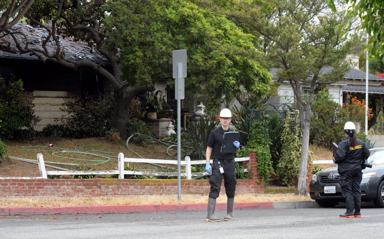 An inspector stands outside the partially burnt house where two bodies were discovered near the Santa Monica College campus.