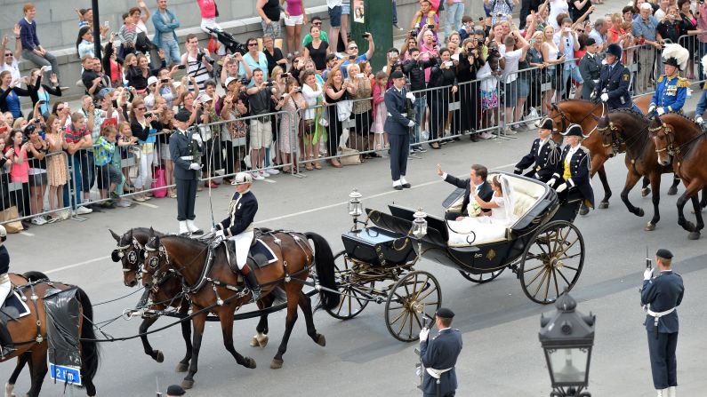 The couple wave to a crowd after the wedding.