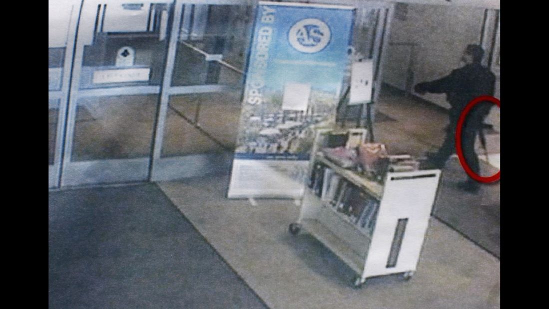 The gunman, carrying what appears to be an assault rifle (circled), enters the library.