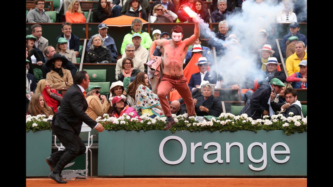 A protester runs onto the court with a lit flare during the match.