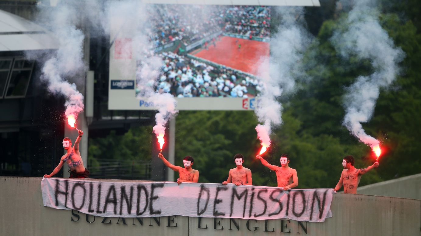 Protesters light flares and unfurl a banner which calls for the French President Francois Hollande's resignation on the top of Court Suzanne Lenglen as Nadal and Ferrer compete.