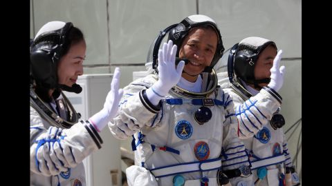 Chinese astronaut Wang Yaping, left, mission commander Nie Haisheng and Zhang Xiaoguang wave to onlookers as they prepare to board on June 11.