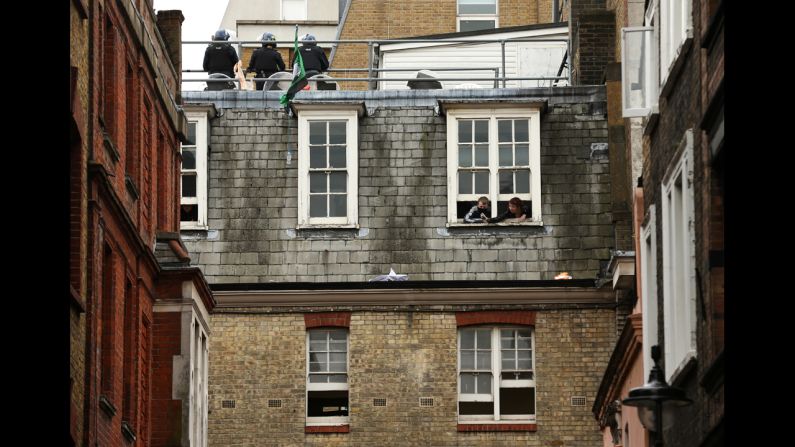 Activists look through windows as police stand guard on the rooftop on June 11.