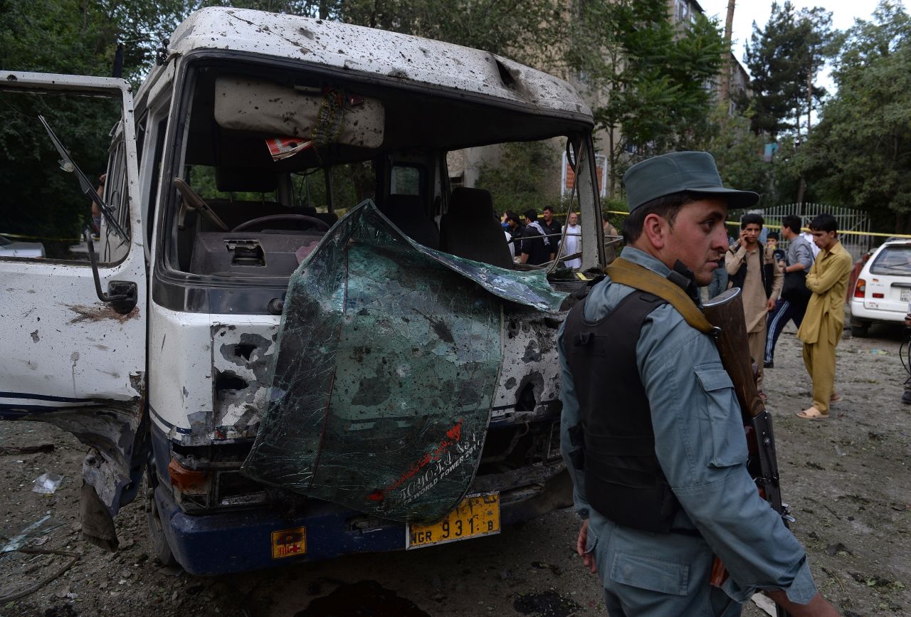 An Afghan policeman stands guard in front of a badly damaged bus at the site of a suicide attack in Kabul on June 11, 2013. More than 1,000 Afghan civilians died in violent attacks in the first half of 2013, according to the U.N.