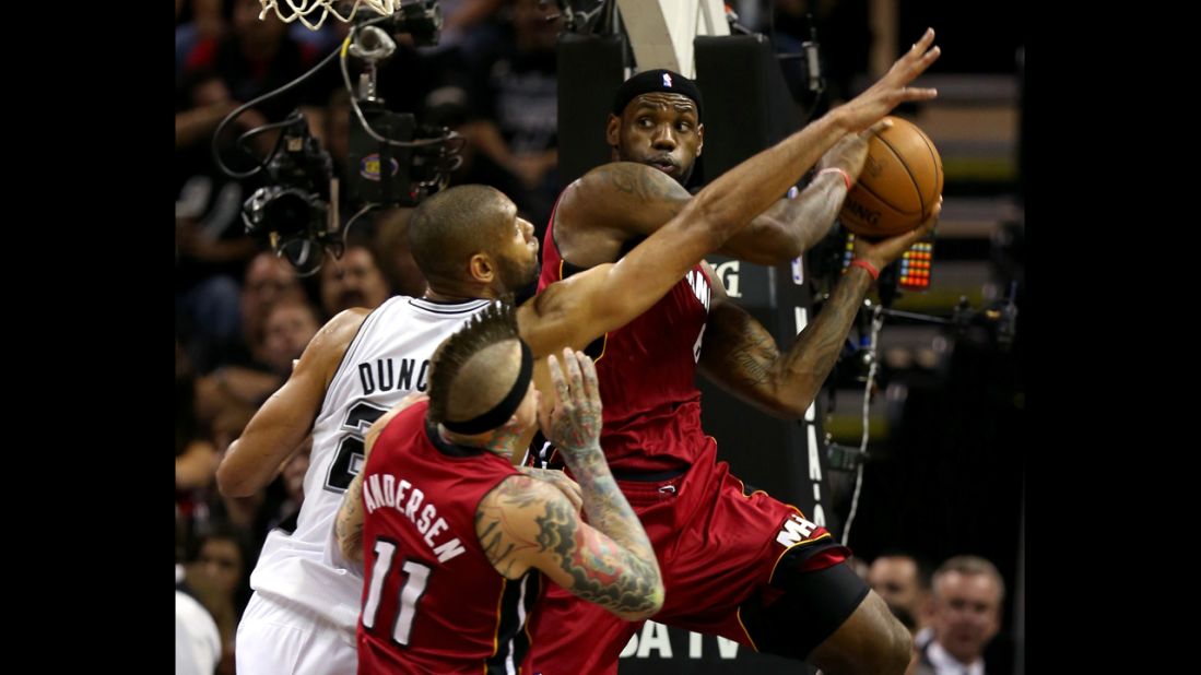 LeBron James of the Miami Heat looks to pass as he is guarded by Tim Duncan of the San Antonio Spurs.