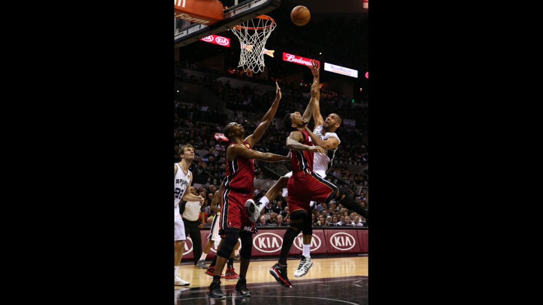 Tim Duncan of the San Antonio Spurs shoots over Udonis Haslem, center, and Chris Bosh, left, of the Miami Heat.