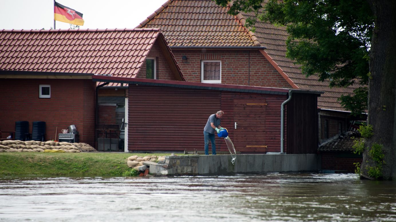 A man empties a bucket of water in front of his house in Hohnstorf, Germany, on June 12.