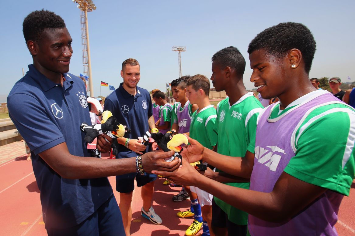 Striker Peniel Mlapa hands out small German mascots to some of the children at the Youth Village. 