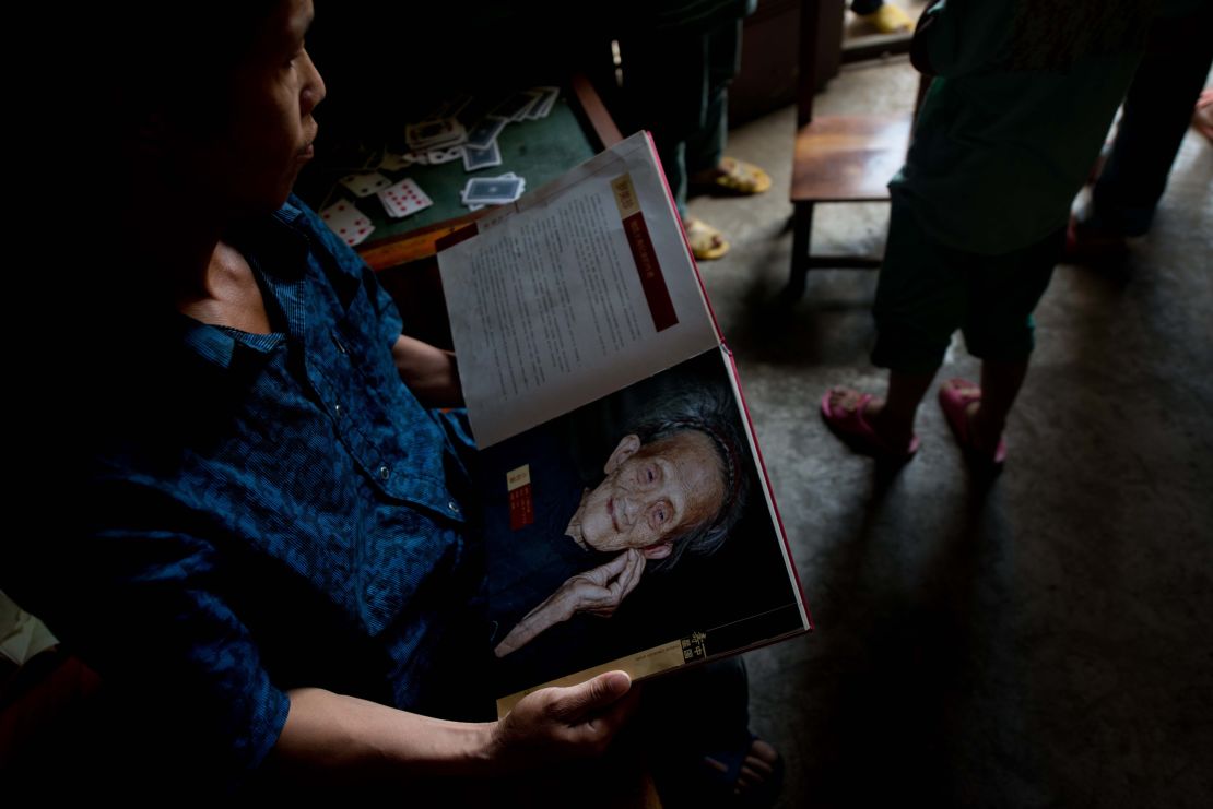 A relative of Luo Meizhen, claimed to be 127, holds her portrait.