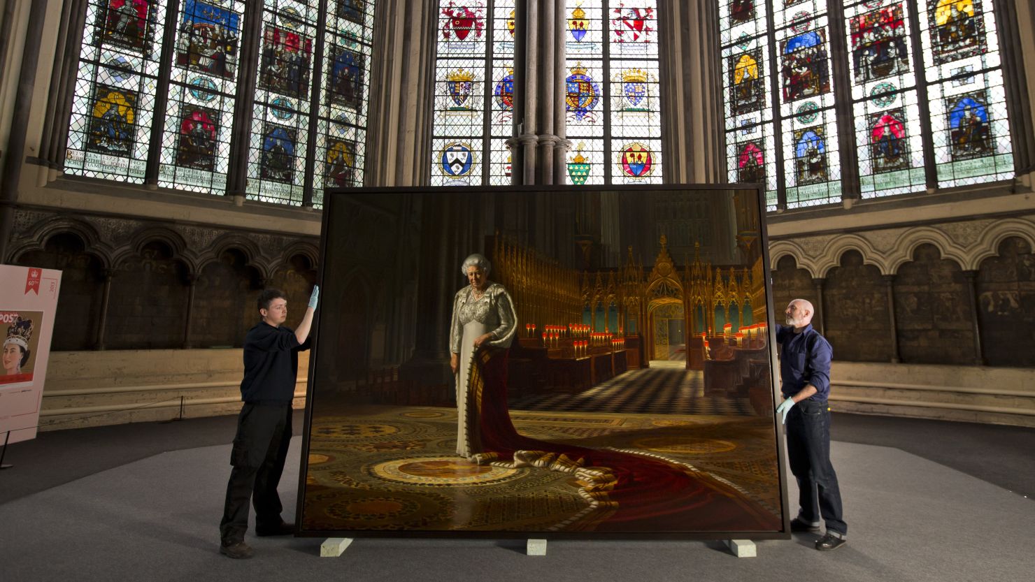 Momart employees hold a portrait of Queen Elizabeth II before it is moved inside Westminster Abbey on May 17, 2013 in London. 