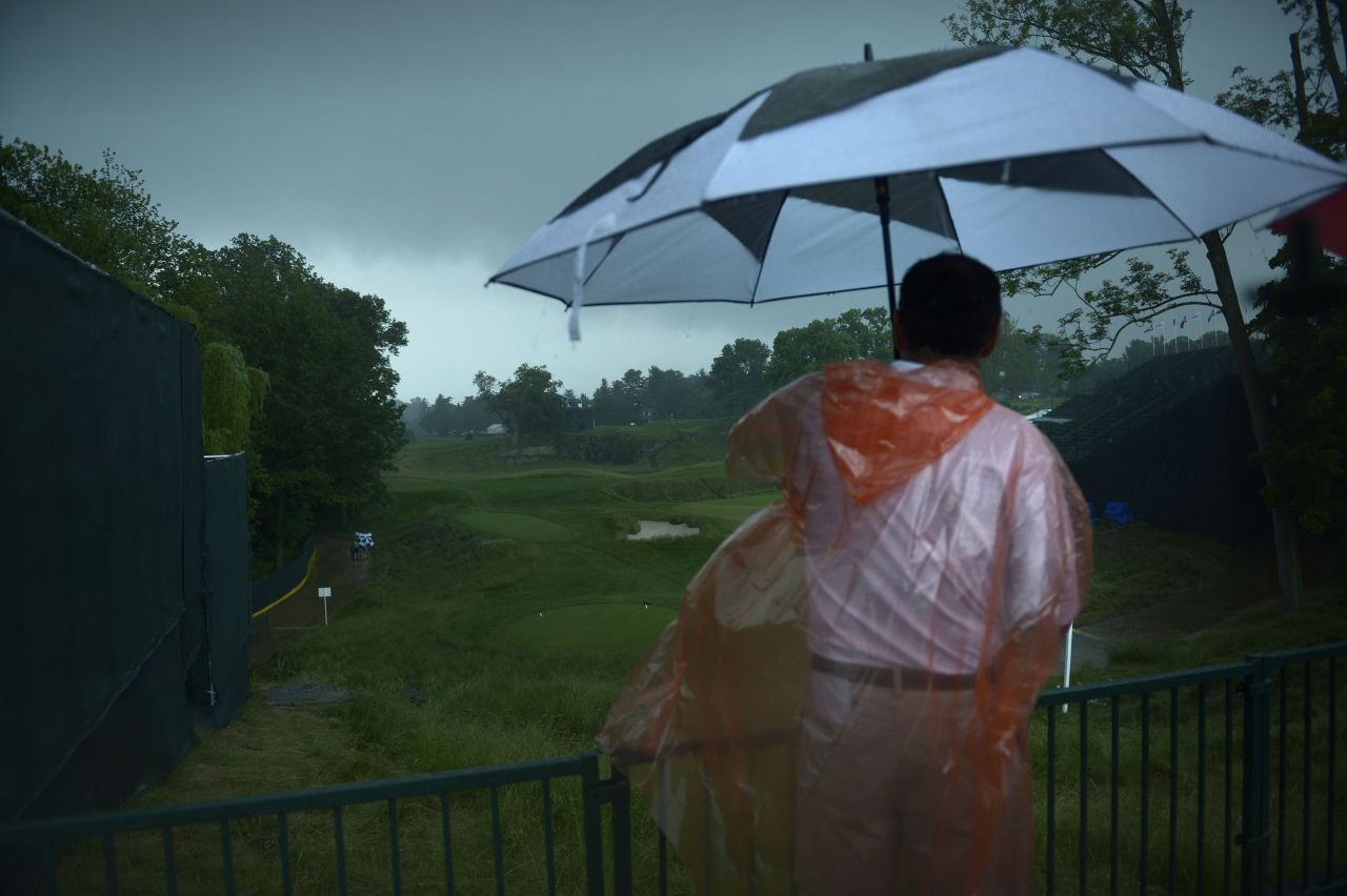 A man looks out over the 18th hole after play was suspended during a storm on June 13.